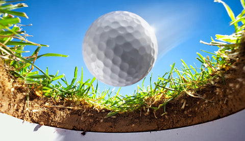 A golf ball dropping into the cup