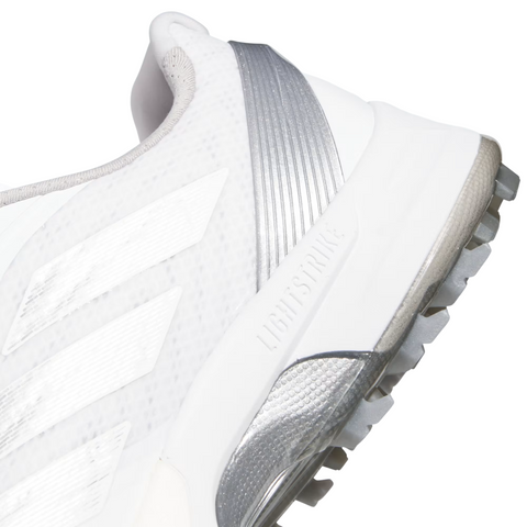 Close-up of Adidas Mens Adizero ZG Spikeless Golf Shoes in white with silver details, three white stripes, a textured grey outsole with patterned grip, and LIGHTSTRIKE embossed on the side. Lightweight design by Adidas.