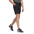 A person, shown from the shoulders down against a white background, is wearing a dark gray shirt, Adidas Men's Ultimate365 8.5" Golf Shorts with a belt, and black and white athletic shoes.