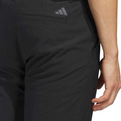 A close-up shows a person in Adidas Ultimate365 Men’s Golf Pants, featuring a gray logo above the back pocket—these moisture-wicking pants offer comfort and style for golfers.