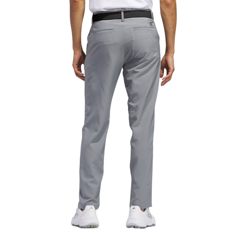 A person is seen from the back wearing Adidas Ultimate365 Mens Golf Pants in light gray, paired with a black belt, white shirt, and white sneakers, set against a white background.