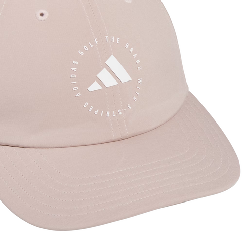 The Adidas Womens Crisscross Hat in Wonder Taupe offers sun protection and style with a white circular Adidas Golf The Brand With 3 Stripes logo on the front—an ideal, fashionable choice for women golfers.