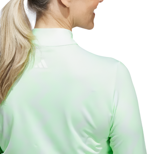 A woman with long blonde hair in a ponytail is seen from behind wearing the Adidas Womens Ultimate365 Printed Quarter-Zip Pullover, a light green, long-sleeved top featuring the Adidas logo on the back of the collar.