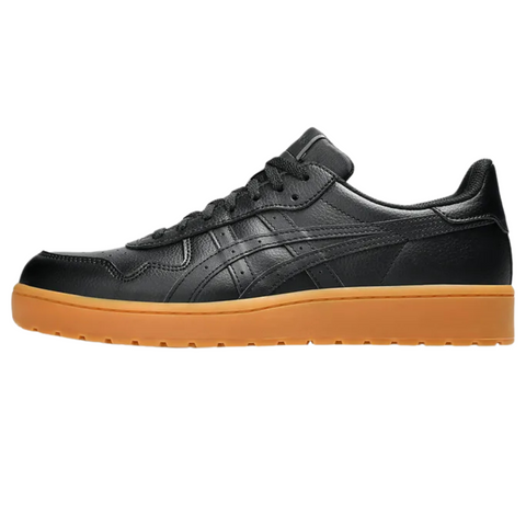 The Asics Japan S Mens Golf Shoes by Asics feature black leather with matching laces and stitching, plus a textured gum-colored rubber sole; shown in side profile on a white background, these stylish shoes evoke modern spikeless golf design.