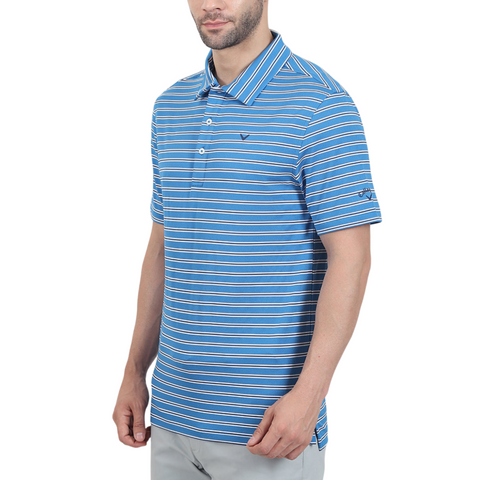 A man wears the Callaway Adelaide Stripe Mens Polo by Callaway—a blue and white striped collared golf shirt with buttons—paired with light gray pants, standing against a plain white background.