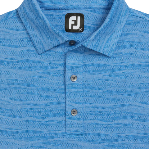 Close-up of the FootJoy Jacquard Wave Mens Polo—a light blue, wavy-textured golf shirt with three grey buttons and a black and white FJ logo tag at the neckline.