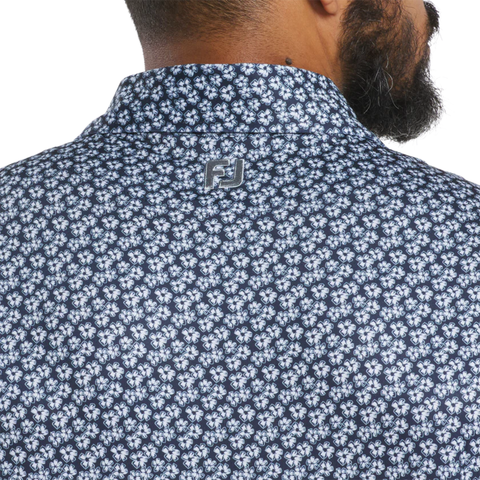 Close-up of a person's back wearing the FootJoy Men's Floral Sketch Print Lisle Polo in Navy/White, featuring a white floral sketch pattern and FJ logo on the collar. Part of their neck, ear, and beard are visible.