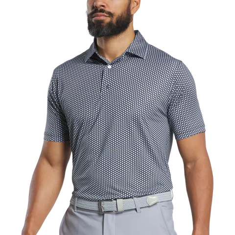 A man with a trimmed beard wears a FootJoy Mens Lisle Houndstooth Geo Print Polo in black, tucked into light gray pants with a matching belt. His head is partially out of frame.