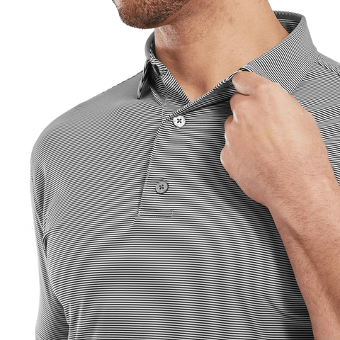 A man wearing the FootJoy Mens Micro Feeder Stripe Lisle Polo in black/grey adjusts the collar with his right hand, showing only the lower half of his face and upper torso.