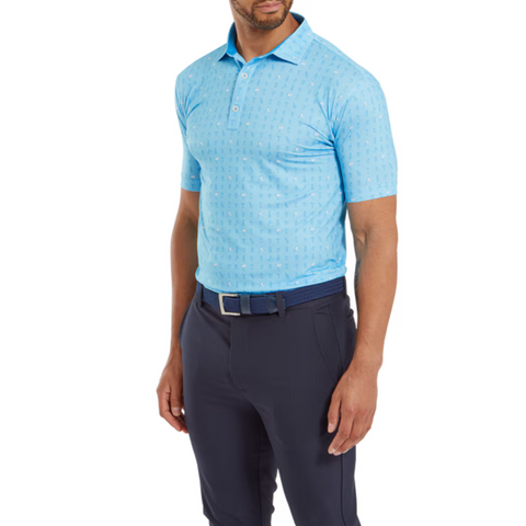 A man wearing a FootJoy The 19th Hole Lisle Mens Polo in light blue with a subtle pattern, dark blue pants, and a matching belt stands against a white background, highlighting this stylish moisture-wicking golf shirt by FootJoy.