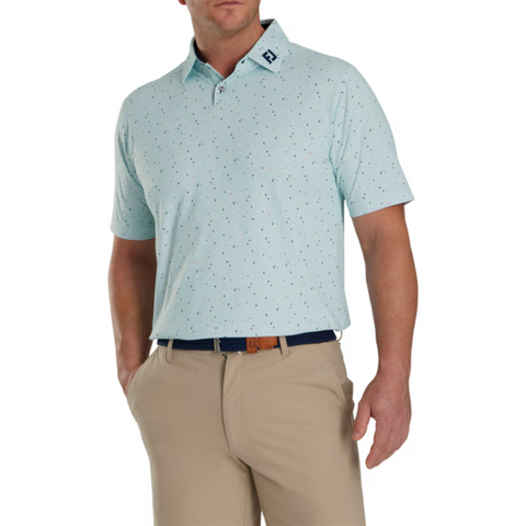 Model wearing the FootJoy Tweed Texture Polo in light mint green, paired with beige pants. The polo features a subtle tweed-like pattern with small, colorful specks. It has a button-up collar and short sleeves, with the FootJoy logo visible on the collar. The model has one hand in his pocket.