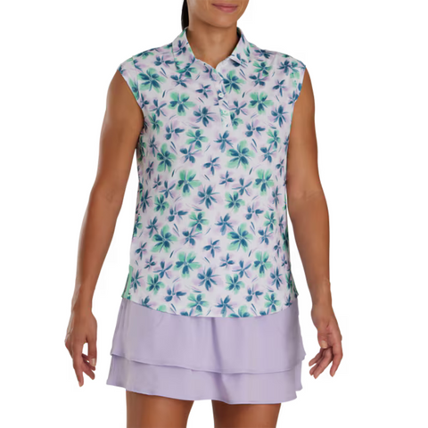Front view of a model wearing a sleeveless floral golf top by FootJoy, featuring a green and blue floral pattern on a white base. Paired with a light lavender pleated golf skirt.