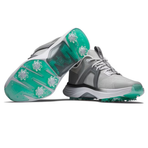 A pair of FootJoy Women's Hyperflex Golf Shoes in grey and teal is displayed; one shoe is upright, the other angled to show the teal spike-studded sole’s pattern. Lightweight and stylish, they offer comfort on the course.
