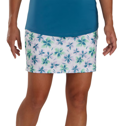 A person wearing a teal top and a FootJoy Womens Performance Knit Skort by FootJoy in white with blue and green floral pattern. Only the lower torso, skirt, and upper legs are shown.