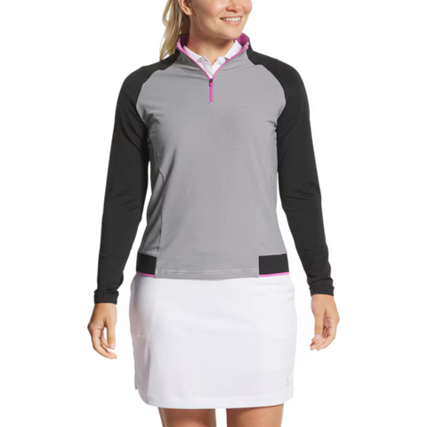A woman models the FootJoy Women's Quarter-Zip Midlayer Top in Black/Grey with a white skirt, standing and smiling against a white background—a stylish choice for women's golf apparel by FootJoy.