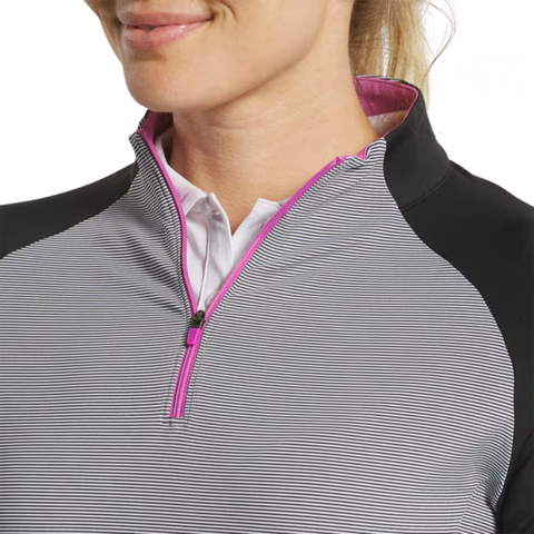 A woman smiles while wearing a FootJoy Women's Quarter-Zip Midlayer Top in Black/Grey, layered over a white collared shirt. Only the lower half of her face and upper torso are visible.