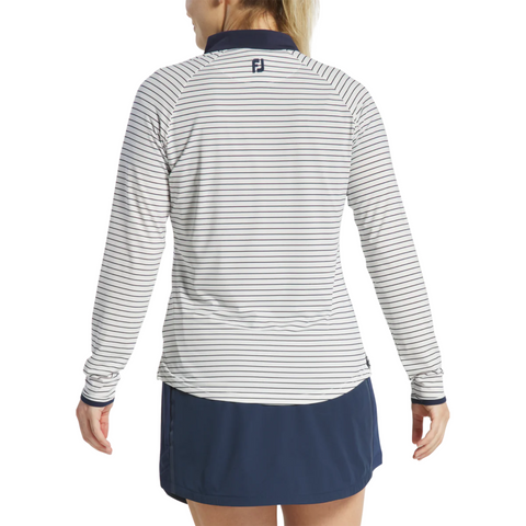 A woman is seen from the back wearing a FootJoy Womens 1/4 Zip Long Sleeve Sun Protection Shirt with thin navy stripes and a navy collar, paired with a navy athletic skirt. The stylish shirt features a small logo below the collar.