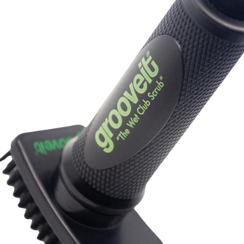 Close-up of a black, textured handle labeled Grooveit Wet Club Scrub Brush in green and white, attached to a Grooveit golf club cleaning brush.