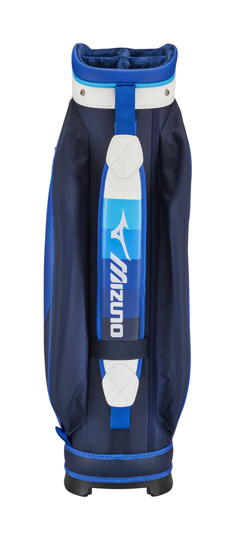 The Mizuno 2025 Tour Cart Bag, in navy blue and white with a blue strap and white accents, stands upright against a plain white background. The Mizuno logo is featured on the strap, showcasing the premium design of this tour-level bag.