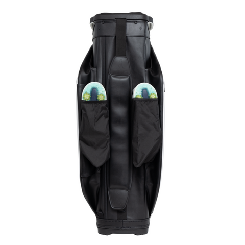 The Ping DLX 244 Cart Golf Bag stands upright in black, showcasing its modern, sleek design and smooth texture. Two side pockets each hold a colorful disc golf disc, partly visible.