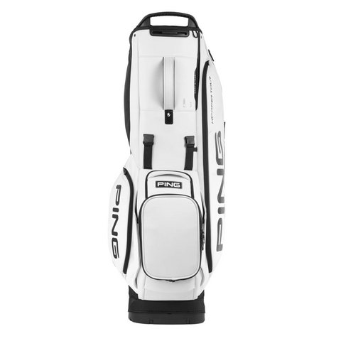 The Ping Hoofer Tour Stand Bag, in white with black accents and lettering, features tour-level storage with multiple zippered pockets and a sturdy base. It stands upright against a white background.