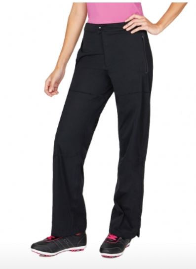 A person wearing Sporte Leisure Ladies Extreme Rain Pants in black, a pink top, and black athletic shoes with pink accents stands with one hand on their hip against a plain background.