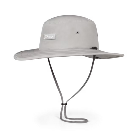 The Titleist Charleston Aussie Bucket Hat in Grey/White features a wide brim, chin strap, front patch, and side eyelets for breathability—offering reliable sun protection and comfort during long days on the golf course.