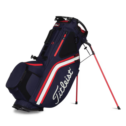 The Titleist Hybrid 14 Golf Bag in navy blue with white and red accents features a 14-way top divider, lightweight design, large side pocket, carrying handle, and extended stand legs. The Titleist logo appears in white on the side.