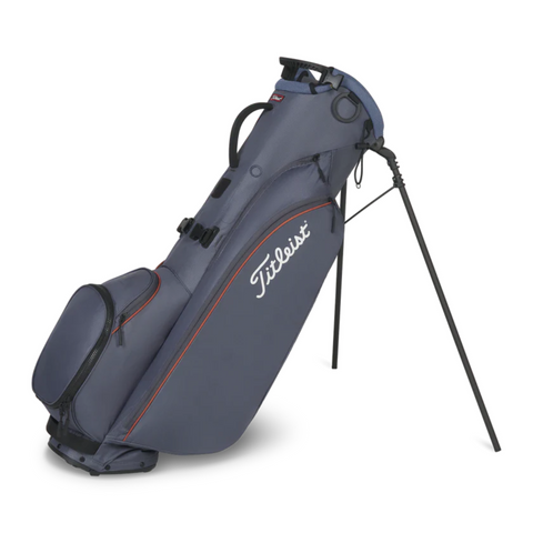 The Titleist Players 4 Carbon Stand Bag 2025 in navy blue with red accents features zippered compartments, a top handle, and ultra-lightweight carbon fiber legs for stability.