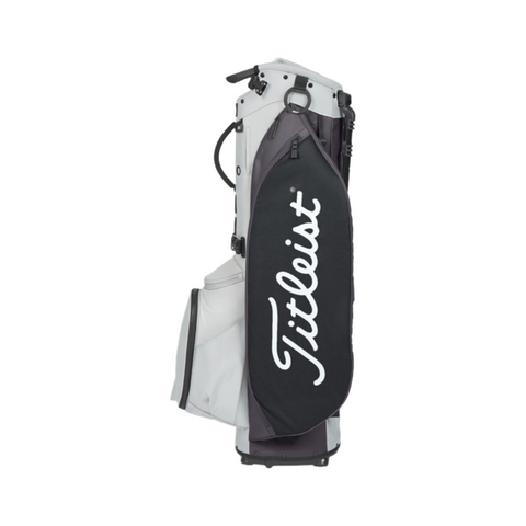 The Titleist Players 5 Stand Bag, in white and black, stands upright on a white background. It features a large side pocket with the Titleist logo in white script, offering golfers both style and functionality.