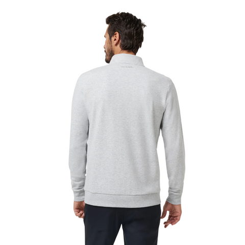 A man stands with his back to the camera, wearing a Travis Mathew Cloud 1/4 Zip 2.0 Men’s Pullover in heather light grey and dark pants, set against a white background.