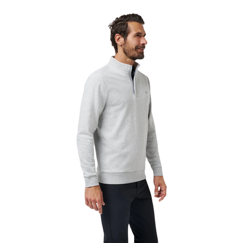 A dark-haired, bearded man smiles in the Travis Mathew Cloud 1/4 Zip 2.0 Men’s Pullover in Heather Light Grey, paired with dark pants against a plain white background.