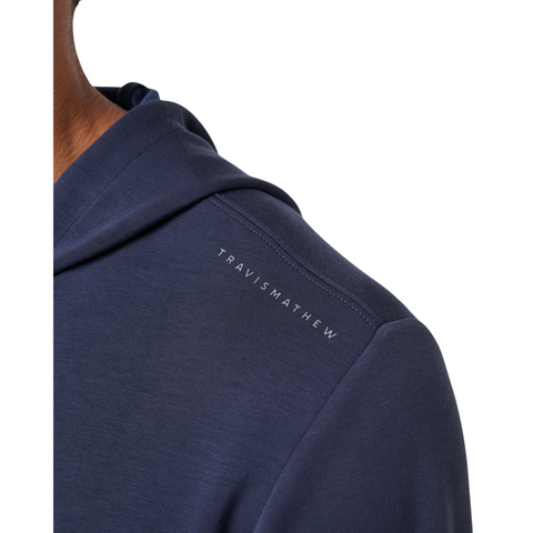 Close-up of a person wearing the Travis Mathew Cloud 1/4 Zip 2.0 Men’s Pullover in Heather Blue, featuring subtle white TRAVIS MATHEW branding on the shoulder, set against a plain white background.