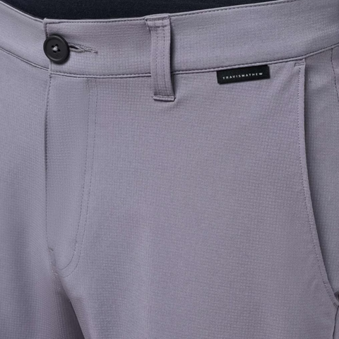 Close-up of light gray Travis Mathew Wanderlust Mens Shorts with button, zipper, belt loops, and a black brand tag above the right pocket. Lightweight with a subtle textured pattern—ideal for golf or casual wear.