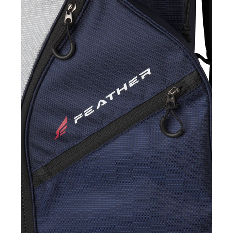 Close-up of the Wilson 2025 Feather Cart Bag in navy blue with black zippers and a white Feather logo beside a red feather icon, printed on the lightweight bag’s zippered front pocket. Brand: Wilson.