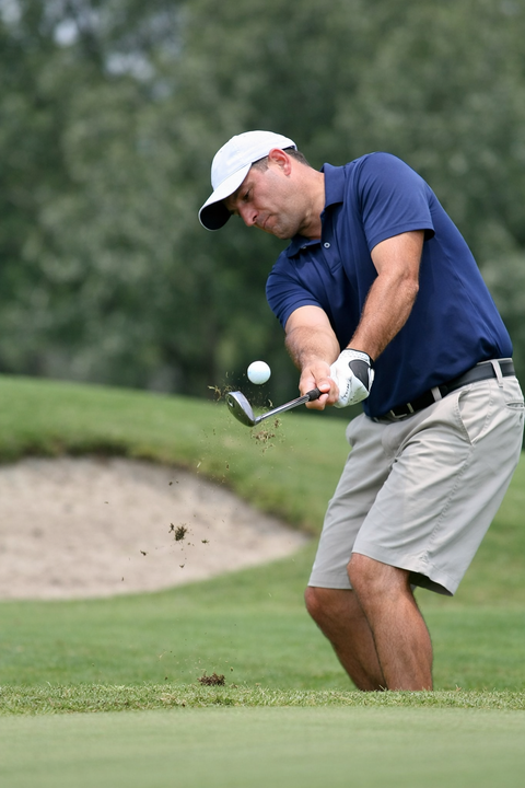A golfer chipping a golf ball into the air
