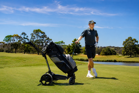 A golfer on course with an MGI Electric Golf Trundler