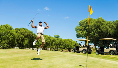 Golf celebrating on the green by jumping in the air