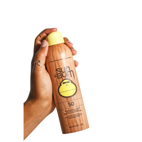 A person holding a can on spray on Sun Bum sunscreen