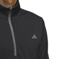 A close-up of a person wearing the Adidas Mens Core Lightweight Zip Top in black, featuring a gray zipper and the Adidas logo on the chest. The background is white.