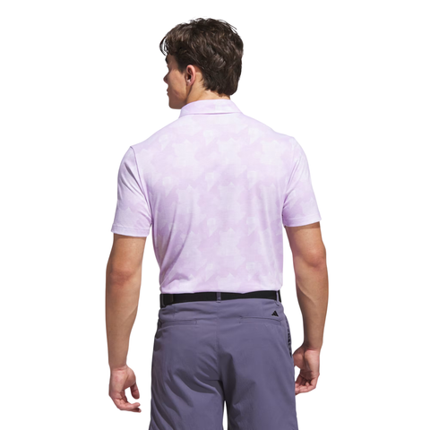 A man with short brown hair is seen from the back wearing an Adidas Men's Go-To Printed Polo Shirt in Powder Plum/White, paired with dark purple pants and a black belt, standing against a white background.