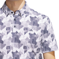 Wearing the Adidas Men's Go-To Printed Polo Shirt in White/Collegiate Navy, a geometric-patterned golf shirt with the Adidas logo.