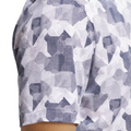 Close-up of a persons upper arm and shoulder wearing the Adidas Men's Go-To Printed Polo Shirt in White/Collegiate Navy, featuring a blue and white geometric pattern with small dots and shapes.