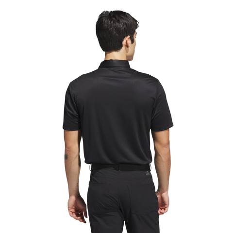 A man with short dark hair stands facing away, wearing the Adidas Men's Performance Allover Print Polo Shirt in black and black pants against a plain white background.