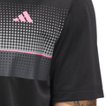 Close-up of a person wearing the Adidas Men's Performance Allover Print Polo Shirt in black, featuring a pink logo and a pattern of white, gray, and pink dots and lines on the chest. Part of the tattooed arm is visible.