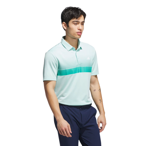 A man stands against a white background wearing the Adidas Mens Performance Chest Stripe Print Polo Shirt in Flash Aqua, a light blue and green gradient golf polo with moisture-wicking fabric, paired with navy blue pants.