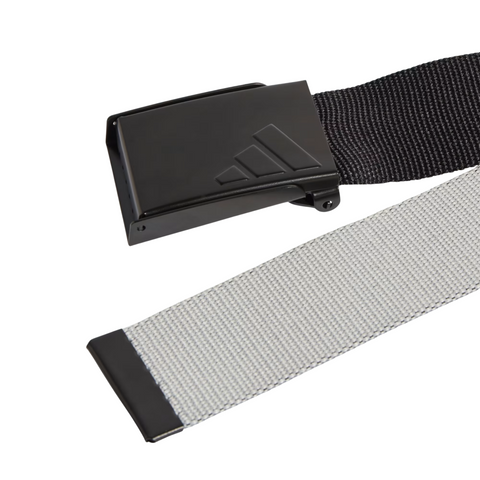 The Adidas Men’s Reversible Webbing Belt in Black/Grey features a black buckle with embossed Adidas logo and a textured, woven strap.
