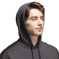 A young man with light skin and brown hair wears the Adidas Mens Ultimate365 Hoodie in dark gray, featuring four-way stretch fleece, hood up, looking slightly right against a plain white background.