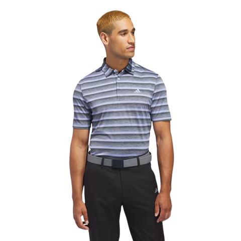 A man with short, light brown hair wears an Adidas Two-Colour Striped Men's Polo Shirt, black pants, and a belt, standing and looking left against a plain white background.