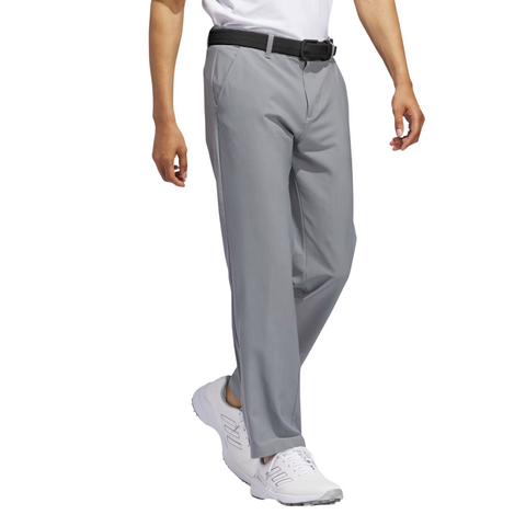 A person is shown from the shoulders down against a white background, wearing Adidas Ultimate365 Men's Golf Pants in light gray, paired with a black belt and white athletic shoes.